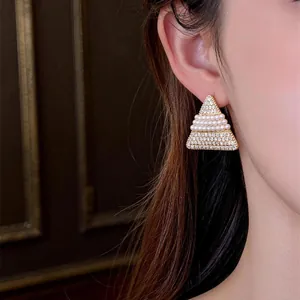 Gros plan d'une boucle d'oreille triangulaire en or 18k avec perles et zircons