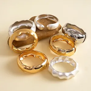 Sammlung von metallischen Wellen- und geometrischen Armreifen in Gold- und Silberoptik