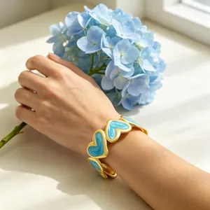Detalle de brazalete en C bañado en oro de 18k con diseño de corazón esmaltado