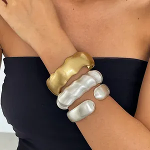 Detailansicht von gestapelten gold- und silbernen wellenförmigen Metallarmbändern