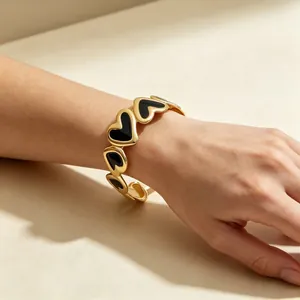 Primer plano de una pulsera de corazón 3D con esmalte negro y un elegante baño de oro 18k