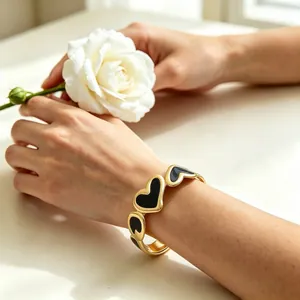 Vista detallada de un elegante brazalete de esmalte de corazón chapado en oro de 18k