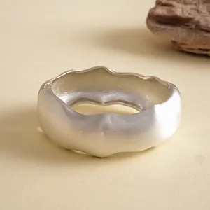 Nahaufnahme des strukturierten silbernen Wellenarmbands mit geometrischem Falten-Design