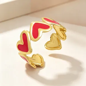 Primer plano de un brazalete en forma de C chapado en oro 18k con corazones de esmalte