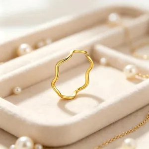 Gros plan d'une bague vague minimaliste en acier titane doré sur plateau velours