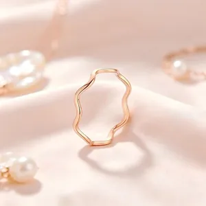 Gros plan macro d'une bague vague minimaliste en or rose sur un fond de tissu rose soyeux