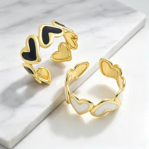 Detalle de brazaletes en C bañados en oro con corazones de esmalte 3D blanco y negro