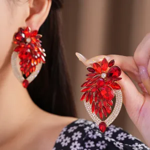 Gros plan détaillé de grandes boucles d'oreilles fleur en cristal rouge et strass brillants