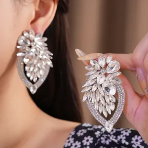 Vue détaillée de boucles d'oreilles fleuries en strass avec aiguilles en argent.