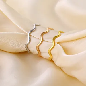 Gros plan de trois bagues vagues empilables de 1 mm en acier titane, or, argent et rose