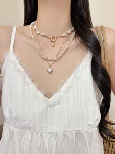 Vue détaillée d'élégants colliers de perles superposés avec pendentif cœur en or