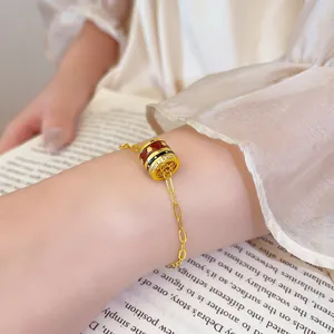 Detailed close-up of a vintage gold-plated bracelet with an enamel charm on the wrist.