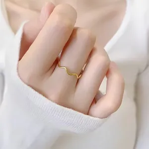 Gros plan d'une bague minimaliste en acier titane plaqué or 18k, forme vague de 1mm.