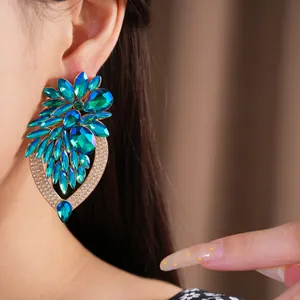 Gros plan de boucles d'oreilles fleurs avec cristaux bleus et verts portées par un mannequin.