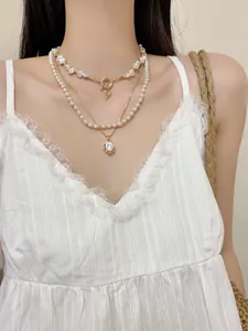 Vue détaillée du collier de perles superposé avec breloque cœur et pendentif perle ovale au cou