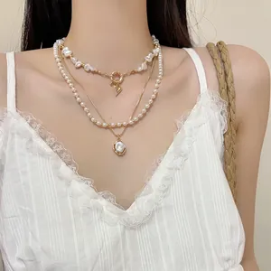 Détail d'un collier de perles vintage multicouche avec charme cœur et pendentif perle ovale