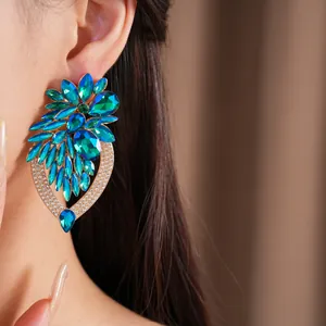 Vue macro de boucles d'oreilles fleurs en cristal bleu avec strass portées par un modèle