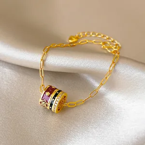 Detail view of 24K gold plated bracelet with enamel and zirconia cylindrical charm