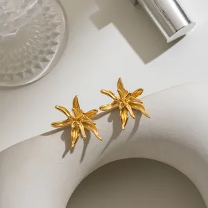 Close-up of elegant gold flower-shaped stud earrings in a minimalist artistic scene