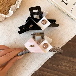 Close-up view of color block geometric hair claw clips featuring a handmade metal emblem
