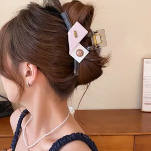 Detailed view of an elegant pink and white geometric color-block hair claw clip in a stylish updo