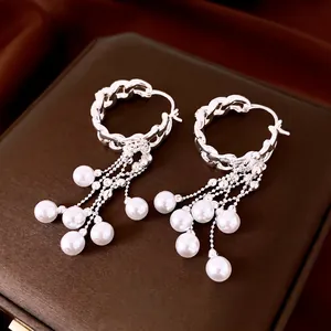 Elegante zilveren creolen met zirkoonketting en witte parelkwastjes op een bruine doos