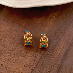 Vintage gold hoop earrings with pearls and turquoise on wood background.