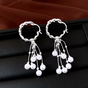 Detail van zilveren gedraaide oorringen met elegante witte parelkwastjes hangers