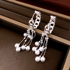 Detailweergave van elegante zilverkleurige kettingkwastoorbellen met witte parelaccenten