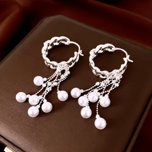 Detailweergave van elegante zilveren kettingoorbellen met kaskaderende parels.