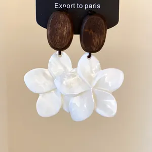 Close-up van vintage houten en witte schelp bloem hangende oorbellen op een kaart