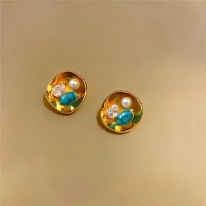 Detailed view of vintage gold-tone stud earrings with pearl, zircon, and turquoise stones