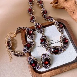 Detailansicht eines Vintage-Schmucksets mit roten Edelsteinen und lila Kristallen auf Tablett