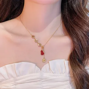 Vue détaillée d'un collier plaqué or 18 carats avec pendentif hulu rouge et symboles Fu