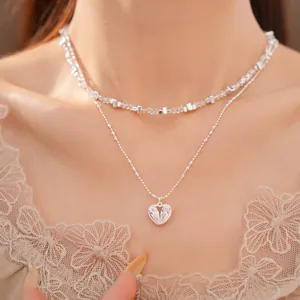 Vista detallada de un collar de plata de doble capa con colgante de corazón de circón brillante.