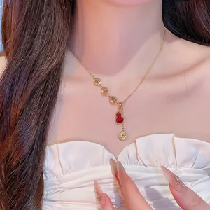 Gros plan d'un collier plaqué or 18k avec des symboles Fu évidés et un pendentif gourde rouge
