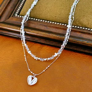 Primer plano de un collar de doble capa con cuentas de vidrio y colgante de corazón.