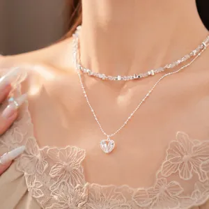 Primer plano de collar de doble capa con colgante de corazón de circón y cuentas de plata