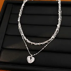Vista detallada de un collar de doble capa con cuentas y colgante de corazón de circón
