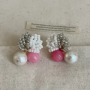 Detailed view of elegant handmade beaded earrings featuring white pearls and pink beads.