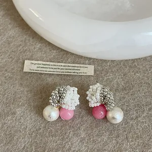 Close-up detail of handmade beaded earrings featuring white pearls and pink bead accents