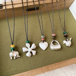 Primer plano de collares de plata cepillata con colgantes de corazón, flor y animales.