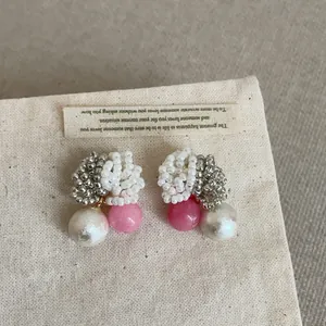 Detailed view of handmade beaded stud earrings with pink and pearl beads on canvas
