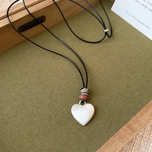 Vista detallada de un collar con colgante de corazón de nácar y cuentas en cordón negro