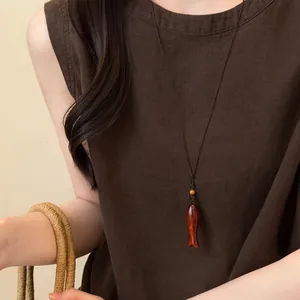 Gros plan d'un collier rétro fait main avec pendentif poisson en bois sur du lin