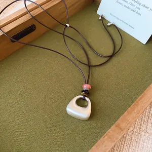 Detalle de un collar con colgante geométrico de plata cepillada y cuentas decorativas