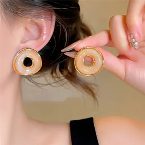 Primer plano de los pendientes redondos vintage con borde dorado y acabado crema