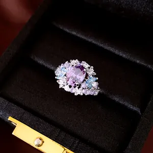 Close-up van een elegante paarse zirkoon ring met blauwe accenten in een doos