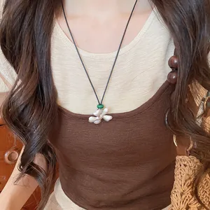 Primer plano de un collar de flores de plata cepillada con cuenta verde en cordón negro para mujer