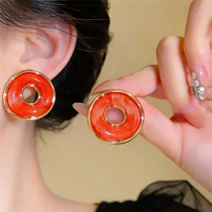 Detalle de pendientes vintage de resina naranja con borde dorado en una modelo.
